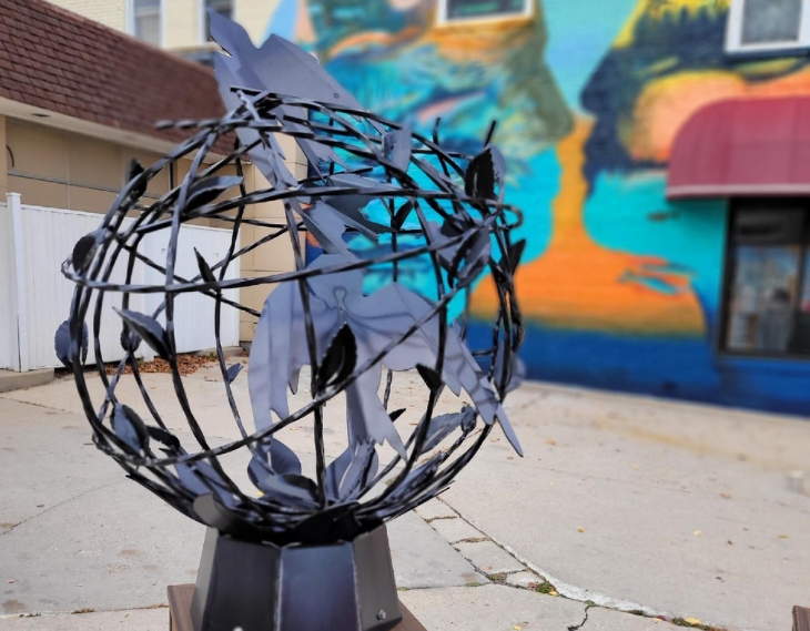 art page The Fifth Day Sculpture resembling a round cage with winged figures in it and escaping